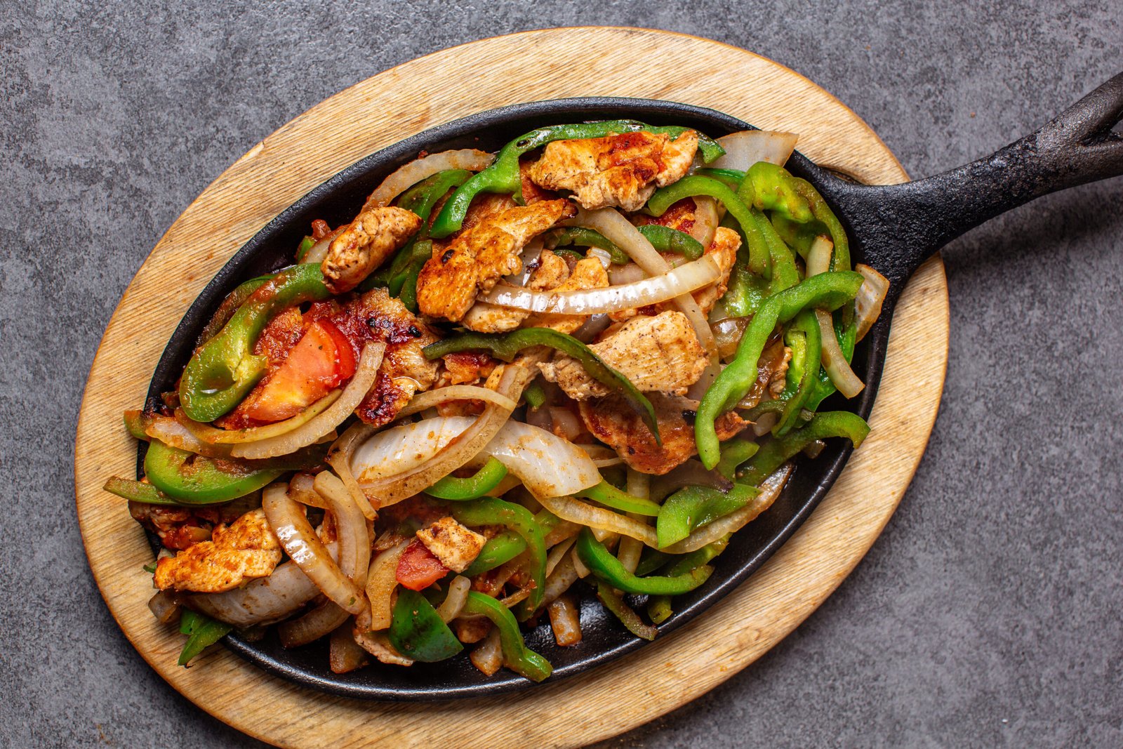Sizzling hot chicken fajitas served on a cast-iron skillet with bell peppers, onions, and tomatoes at a top-rated restaurant in Downtown Chattanooga.