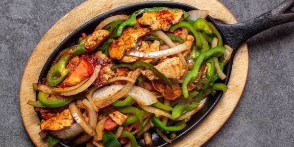 Sizzling hot chicken fajitas served on a cast-iron skillet with bell peppers, onions, and tomatoes at a top-rated restaurant in Cleveland TN. Sizzling hot chicken fajitas served on a cast-iron skillet with bell peppers, onions, and tomatoes at a top-rated restaurant in Cleveland TN.